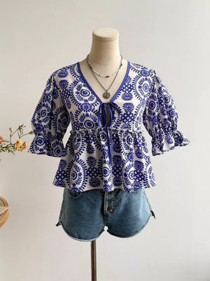 Chic floral tie-front blouse with 3/4 puff sleeves and peplum hem, styled with denim shorts.