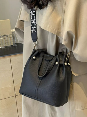 Black textured crossbody bag with unique patterned strap and silver hardware.