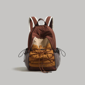 Brown nylon backpack with adjustable bungee drawstring and mesh side pockets.