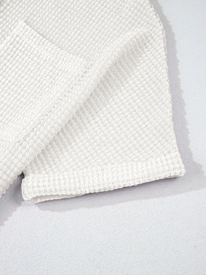 White waffle knit button-up shirt detail showing texture and rolled sleeve cuff.