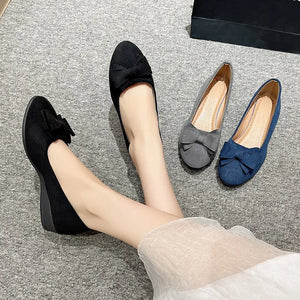 Black suede ballet flats with bow detail, shown with dark gray and navy flats.
