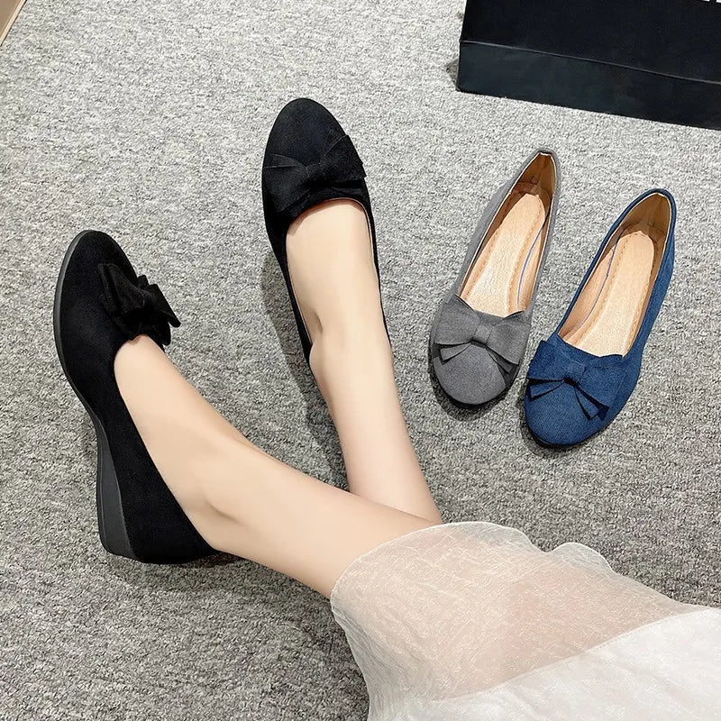 Black suede ballet flats with bow detail, shown with dark gray and navy flats.