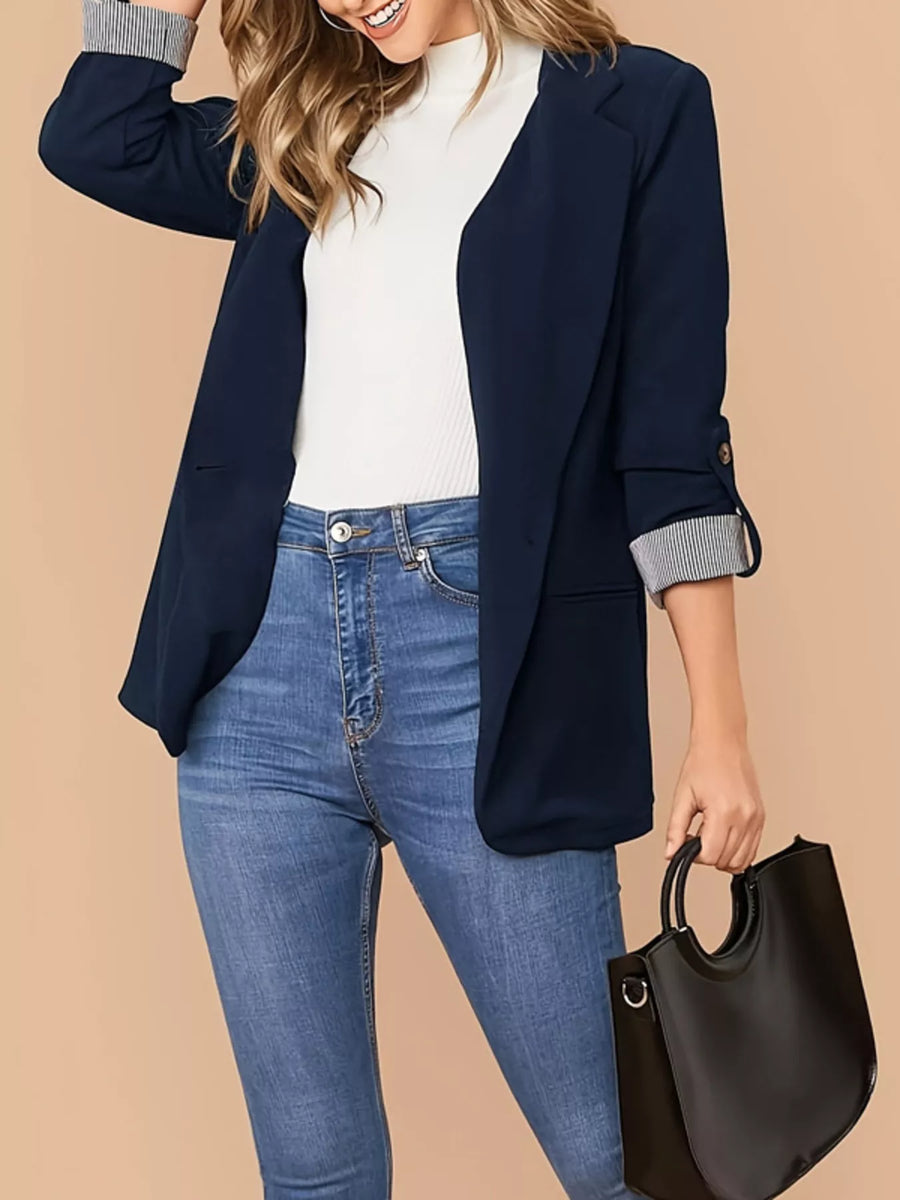 Navy blue blazer with one button and striped roll-up sleeves, styled with jeans.