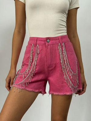 Fuchsia pink denim shorts with rhinestone embellishments and chain fringe detail.