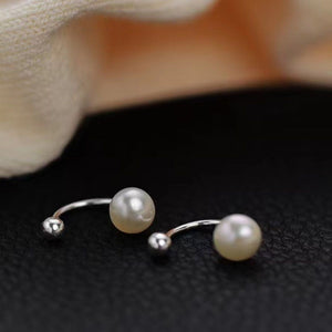 Sterling pearl stud earrings with curved silver posts and small ball accents.