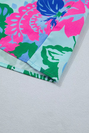 Vibrant floral print blouse with V-neck and relaxed fit, featuring bright pink, blue, and green flowers on a light blue