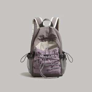 Lightweight nylon backpack in grey with purple drawstring front pocket and mesh side pockets.
