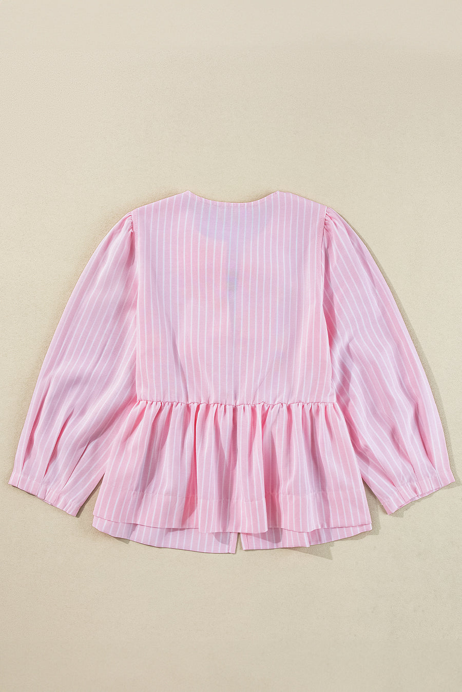 Blush pink striped peplum blouse with long puff sleeves and a ruffled hem.