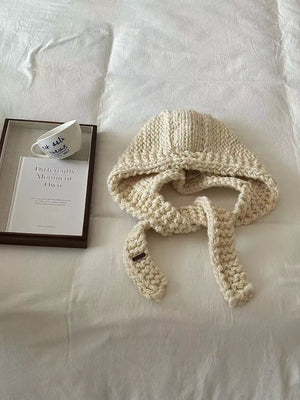 Off-white wool earflap beanie with chunky knit and ties.