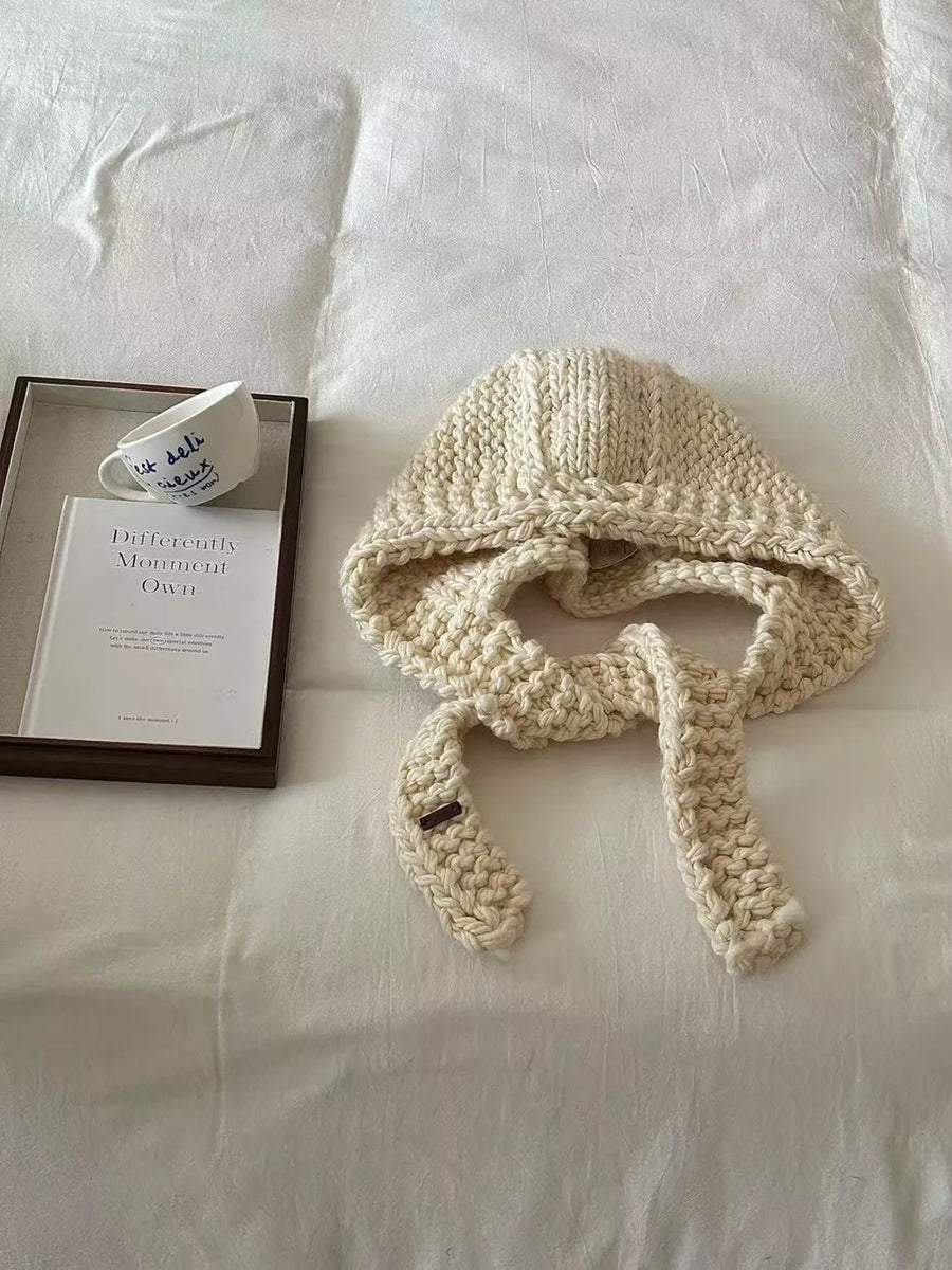 Off-white wool earflap beanie with chunky knit and ties.