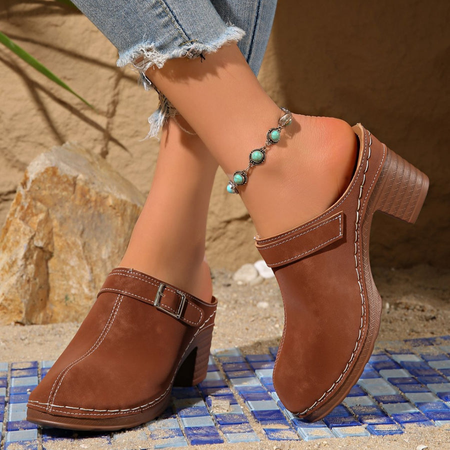Brown round toe platform slip-ons with buckle detail and white stitching.