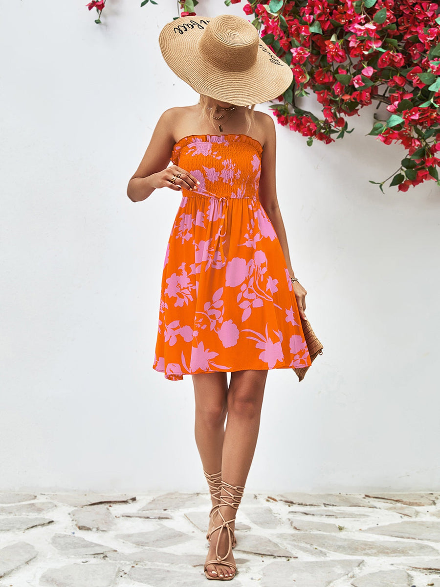 Orange floral smocked bandeau mini dress with drawstring waist and ruffled hem.