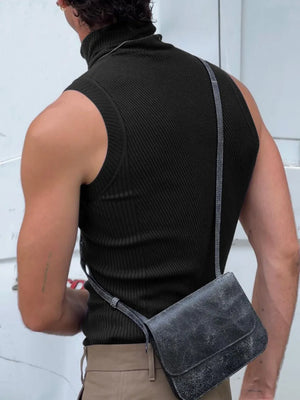 Black ribbed sleeveless turtleneck shirt with a high neck, styled with a crossbody bag.