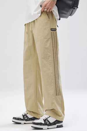 Khaki cargo pants with adjustable drawstring waist and side stripe detail.