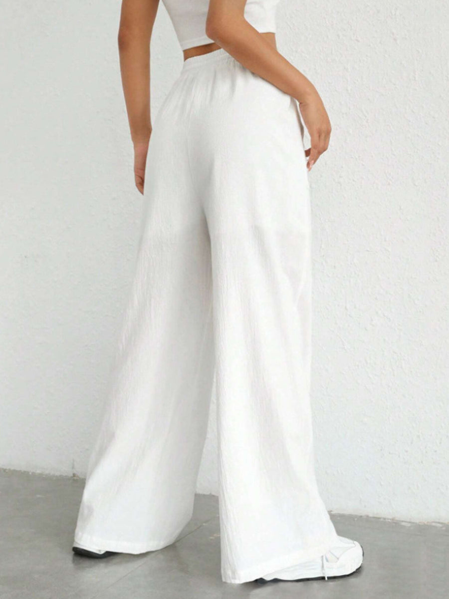 White linen wide-leg drawstring trousers with a relaxed fit.