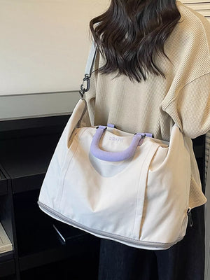 Sleek nylon travel bag in off-white with purple handles and adjustable strap.