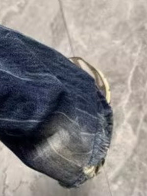 Men's distressed blue denim jeans with a baggy fit and pocket detail.