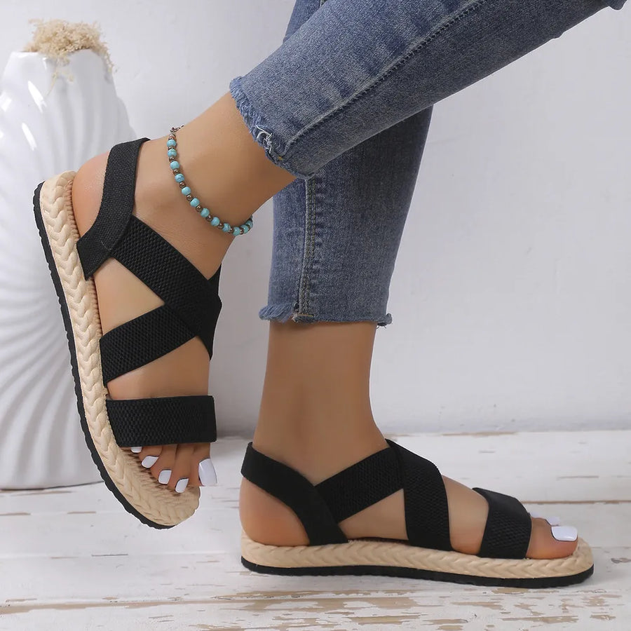 Black crisscross elastic summer sandals with braided espadrille sole detail.