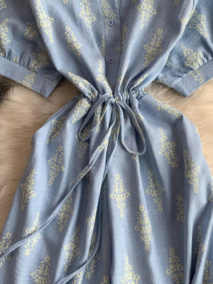 Blue patterned maternity jumpsuit with drawstring waist and button front detail.