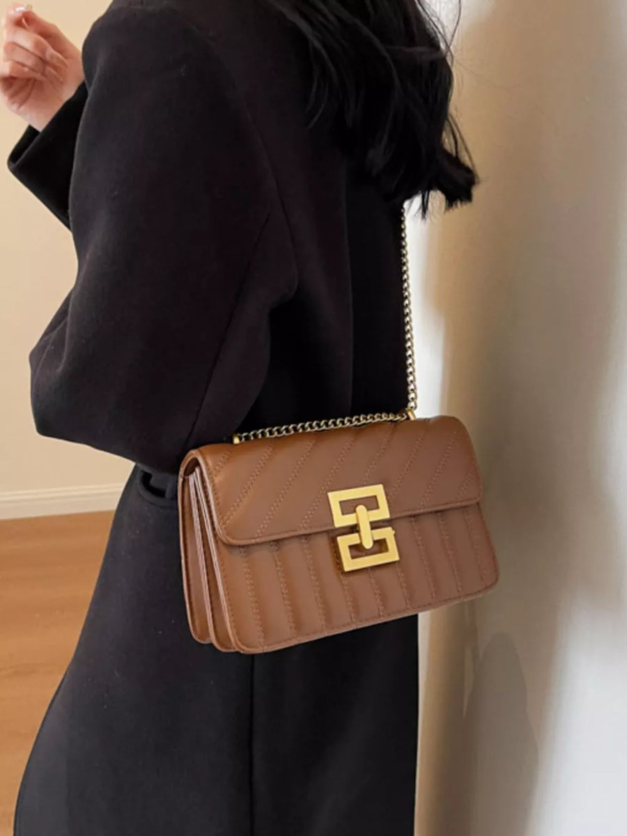 Chic quilted crossbody bag in brown with gold chain strap and clasp.