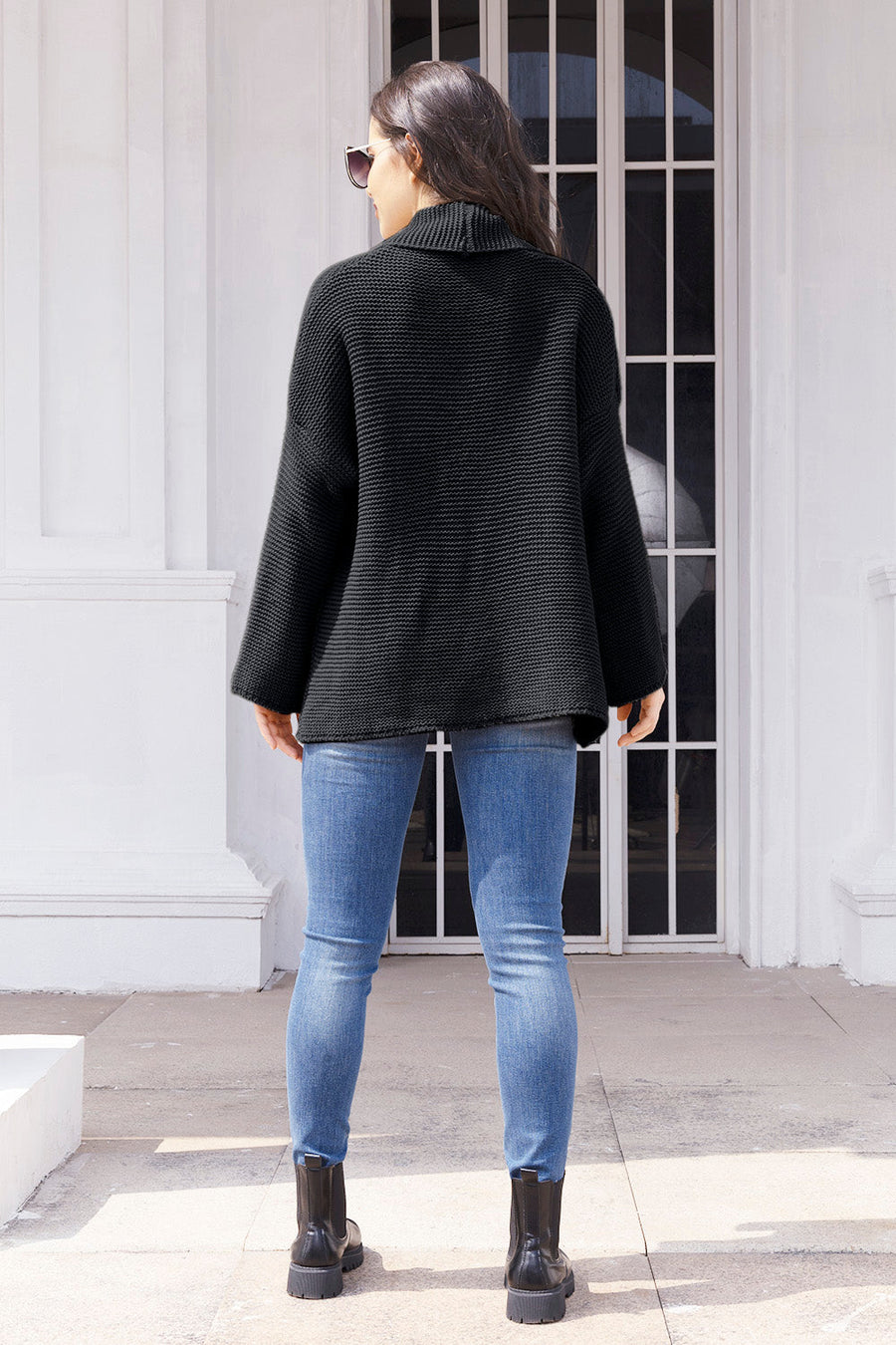 Black waffle knit cardigan with a shawl collar and relaxed fit, worn with jeans.