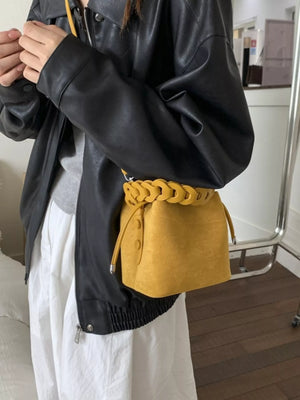 Yellow mini crossbody bag with braided chain strap and drawstring closure.