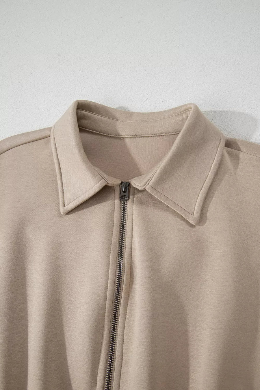 Chic collared zip front romper in beige with cap sleeves.
