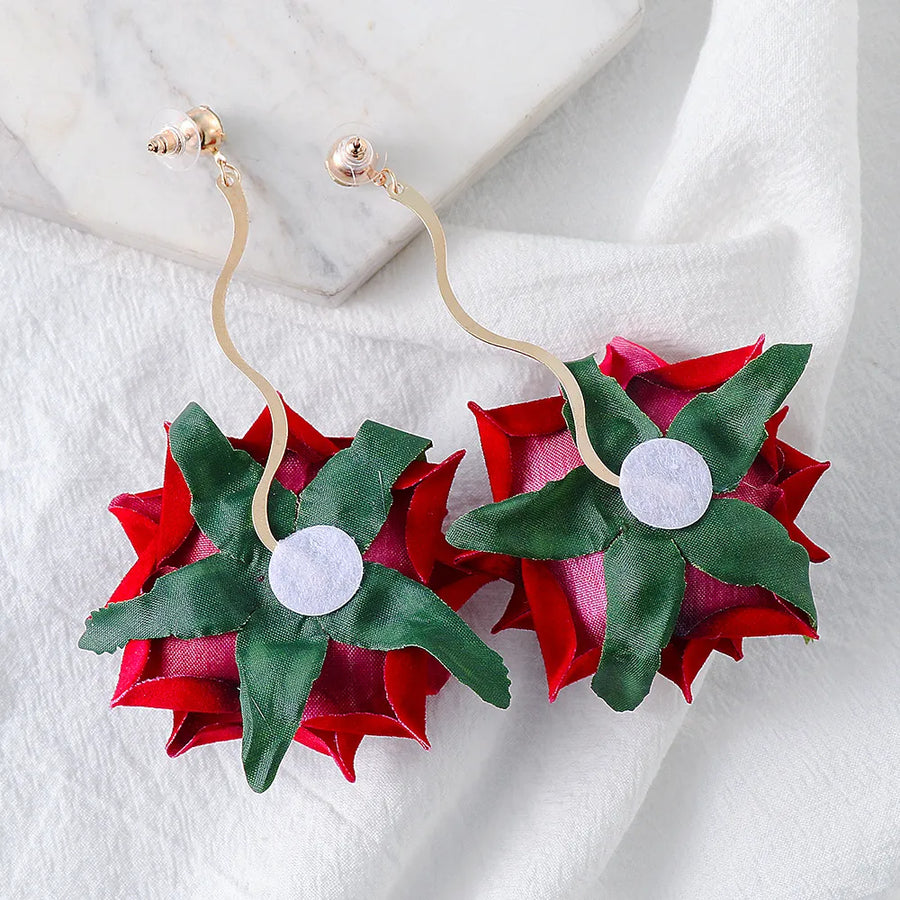 Velvet rose cascade earrings in deep red with green leaves and gold wavy stems.