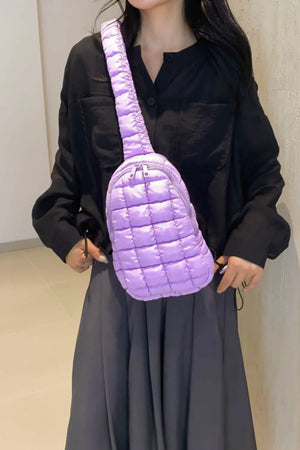 Padded sling bag with top handle in pastel blue, quilted design, and adjustable strap.