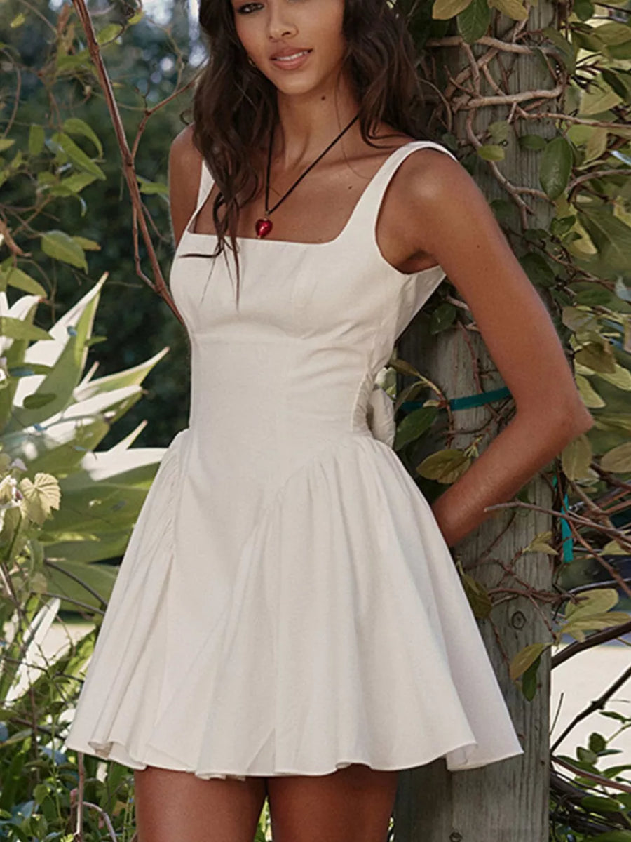 White backless mini dress with square neckline and bow detail.