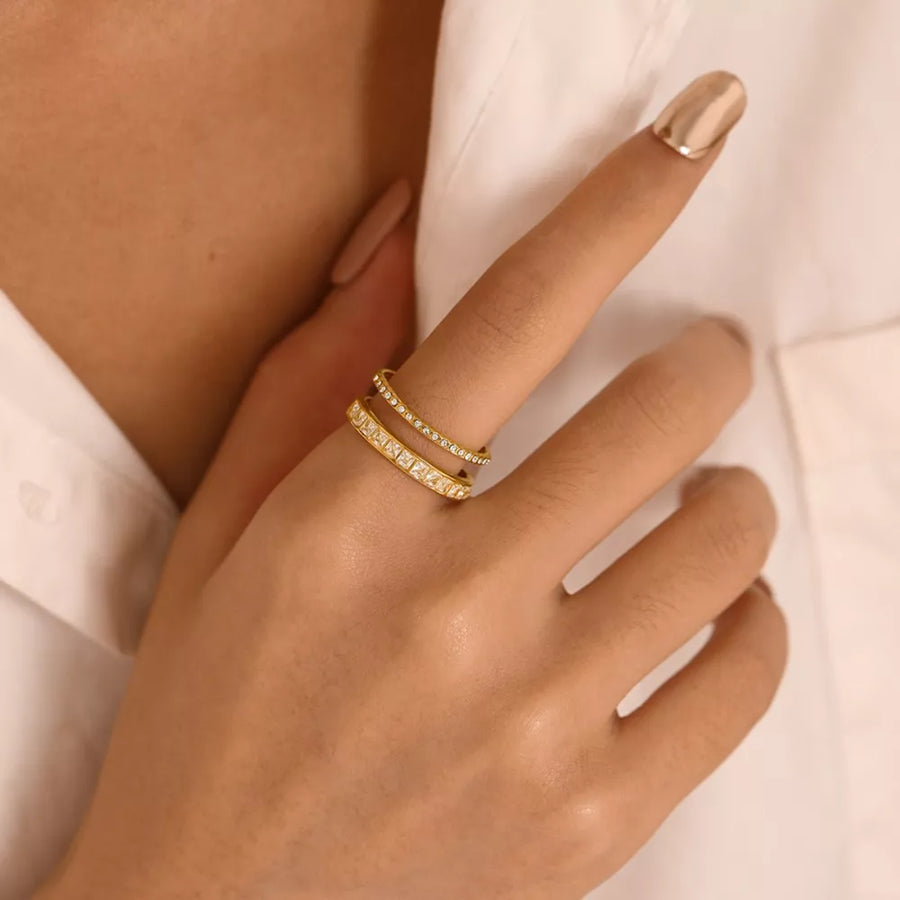 Gold-plated open ring with two bands, one set with square rhinestones, the other with small clear stones.