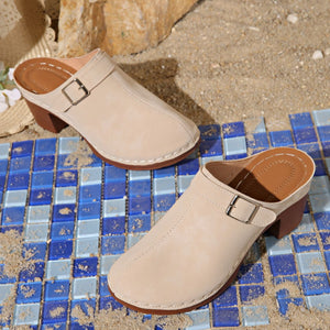 Beige round toe platform slip-on heels with buckle detail and block heel.