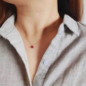 Gold delicate necklace with a small red heart zircon pendant.