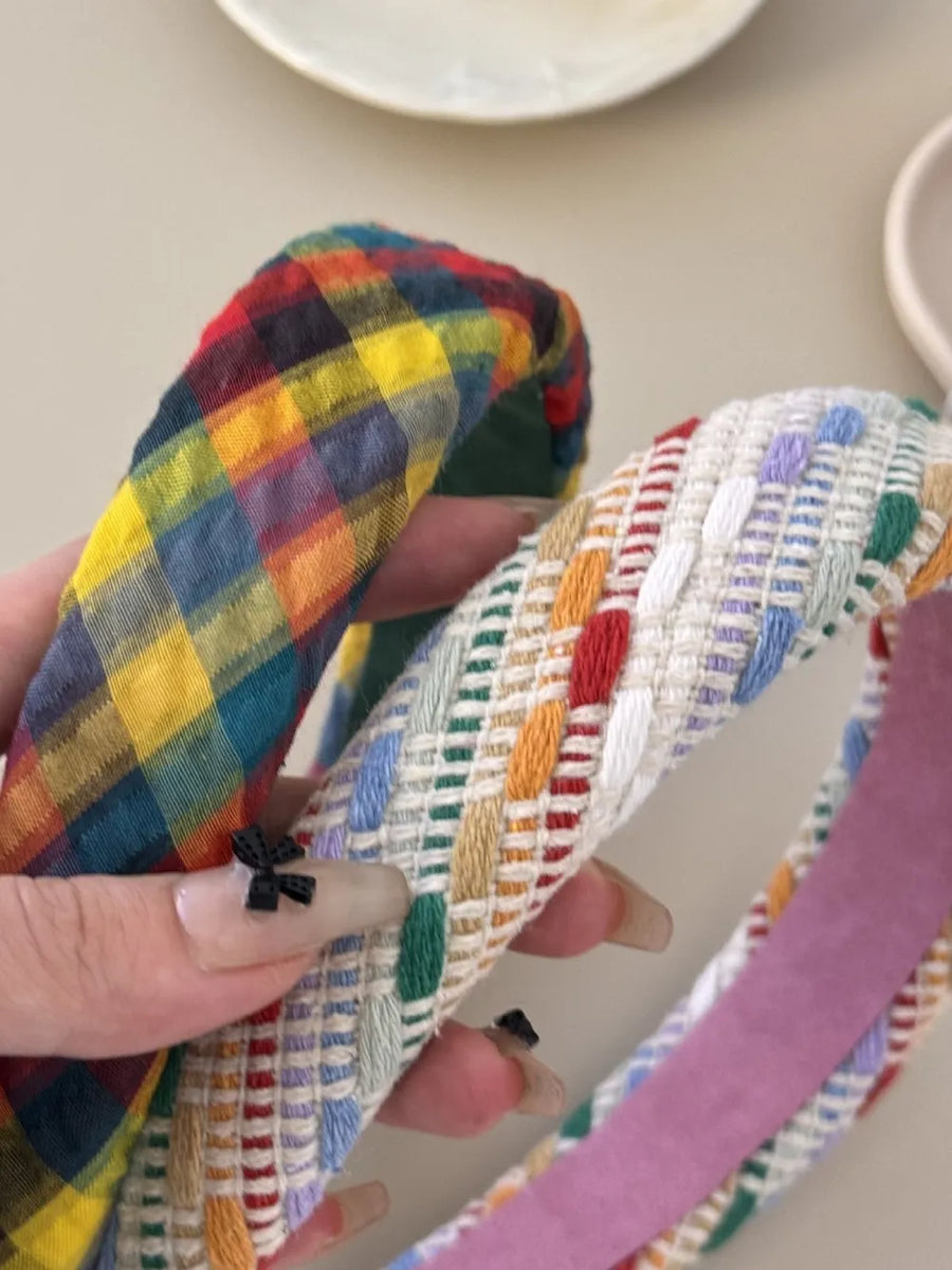 Plaid and multi-colored woven padded headbands with textured fabric and a small bow detail.