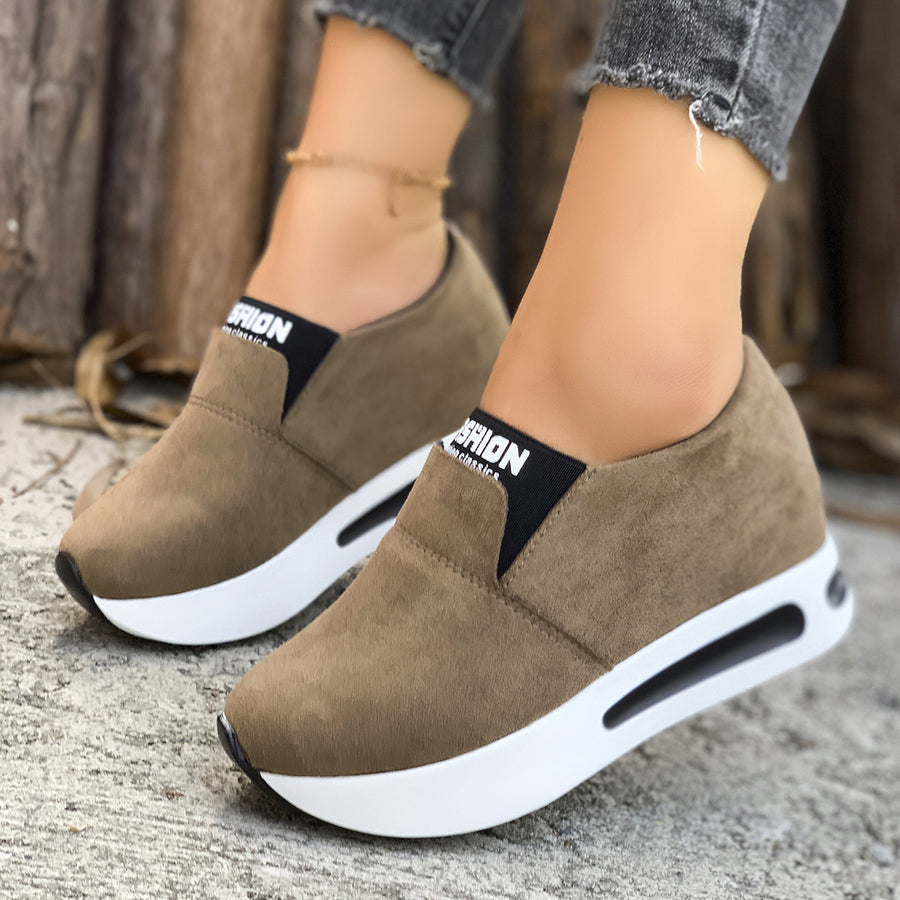 Dark brown round toe slip-on sneakers with white platform soles and black elastic trim.