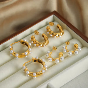 Gold hoop earrings with pearls, featuring sculpted and curved designs.