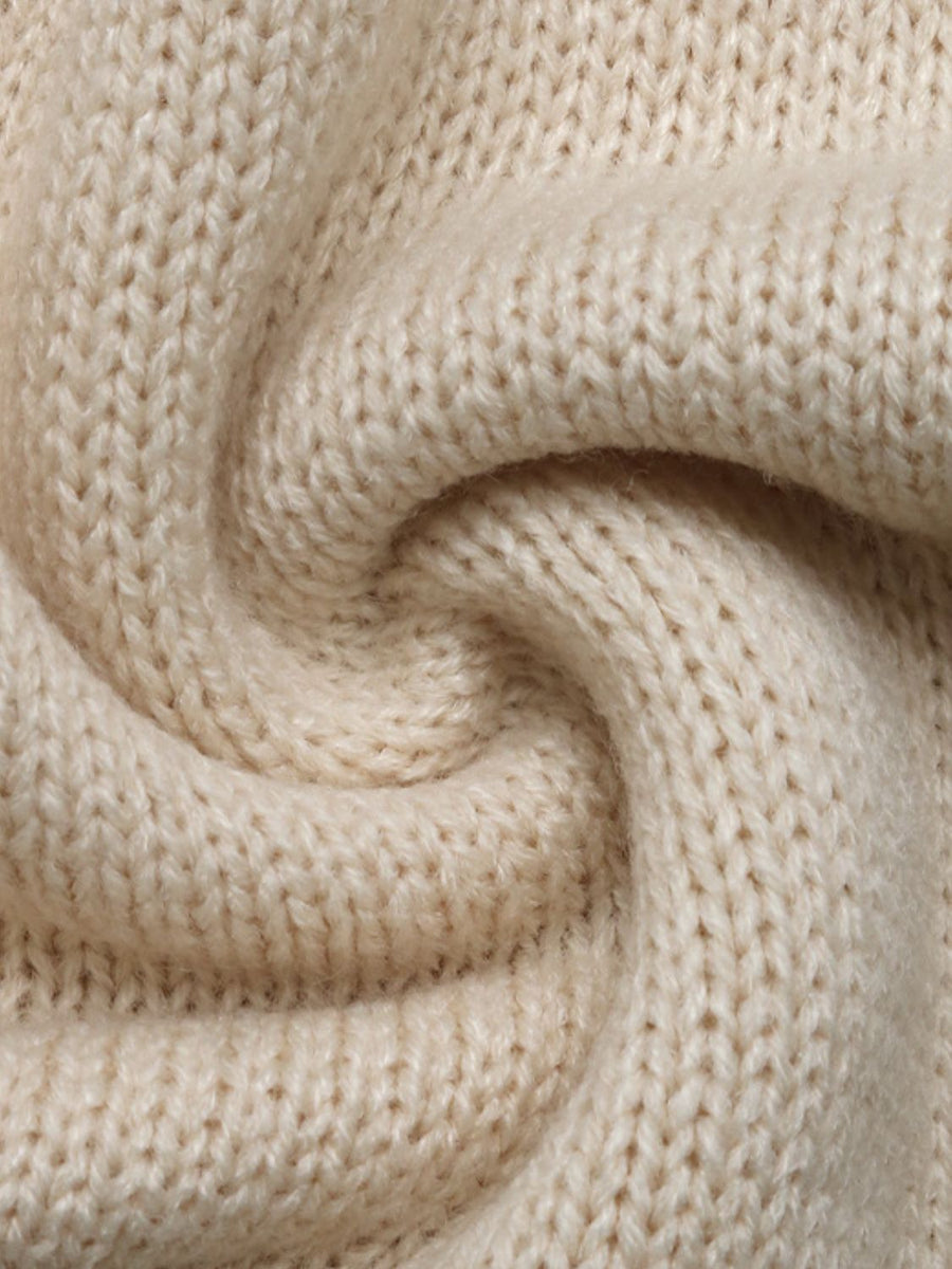 Cream acrylic knit cardigan detail showing textured stitches and soft fabric.
