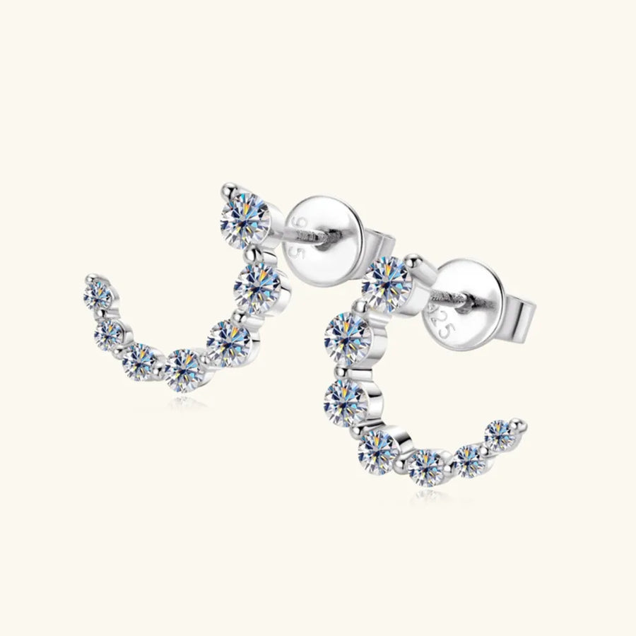 Silver celestial arc moissanite stud earrings with sparkling stones.