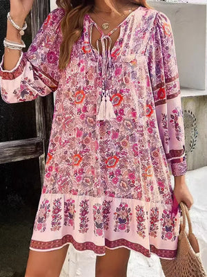 Vibrant floral tassel tie mini dress in blush pink with long sleeves and tiered hem.