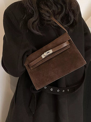 Elegant buckle shoulder bag in coffee color suede with a silver clasp and brown trim.