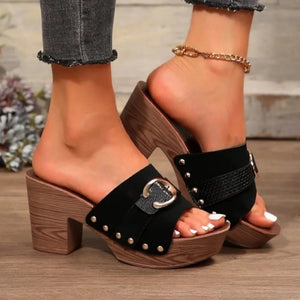 Black platform mule with buckle detail and studded trim on a wooden heel.