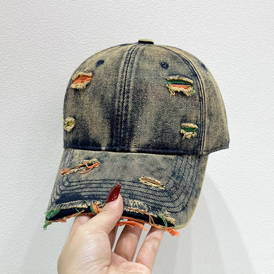 Distressed denim baseball cap with fraying and colorful threads visible through rips.