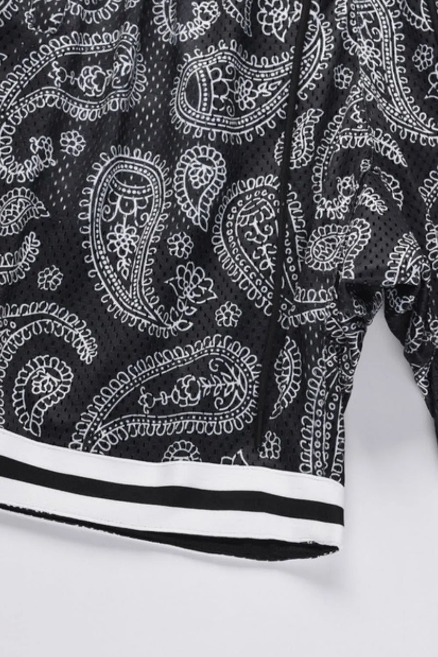 Black mesh basketball shorts with white paisley pattern and striped hem.