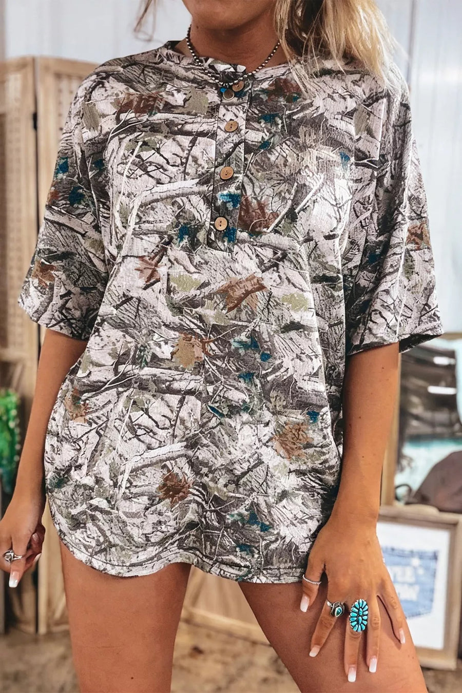 Earthy camouflage print henley t-shirt with button detail and short sleeves.