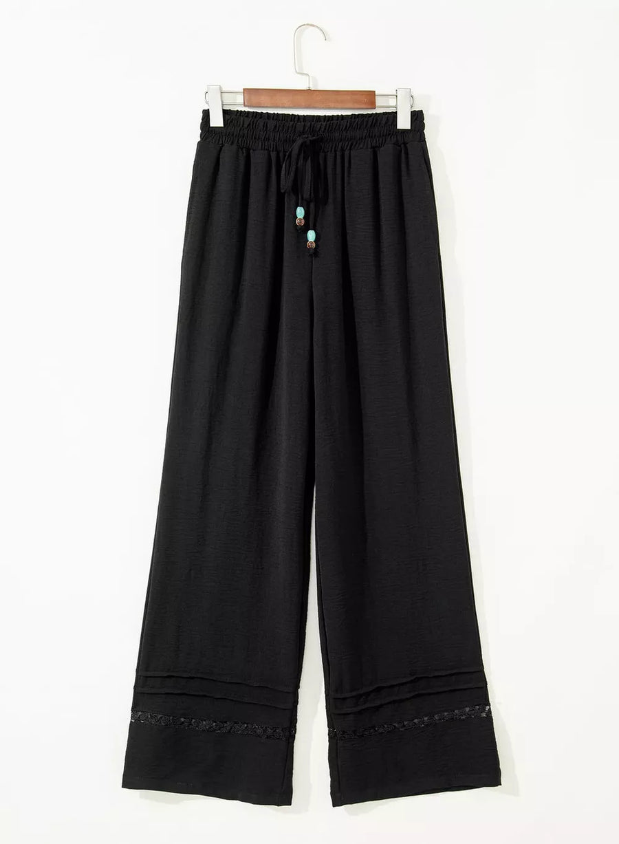 Black maternity wide-leg trousers with drawstring and beaded detail.