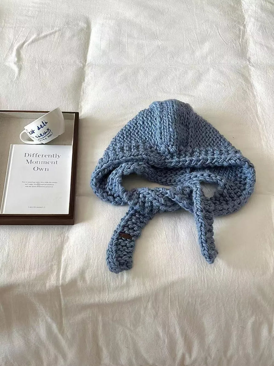 Blue wool earflap beanie hat with chunky knit texture and tie closures.