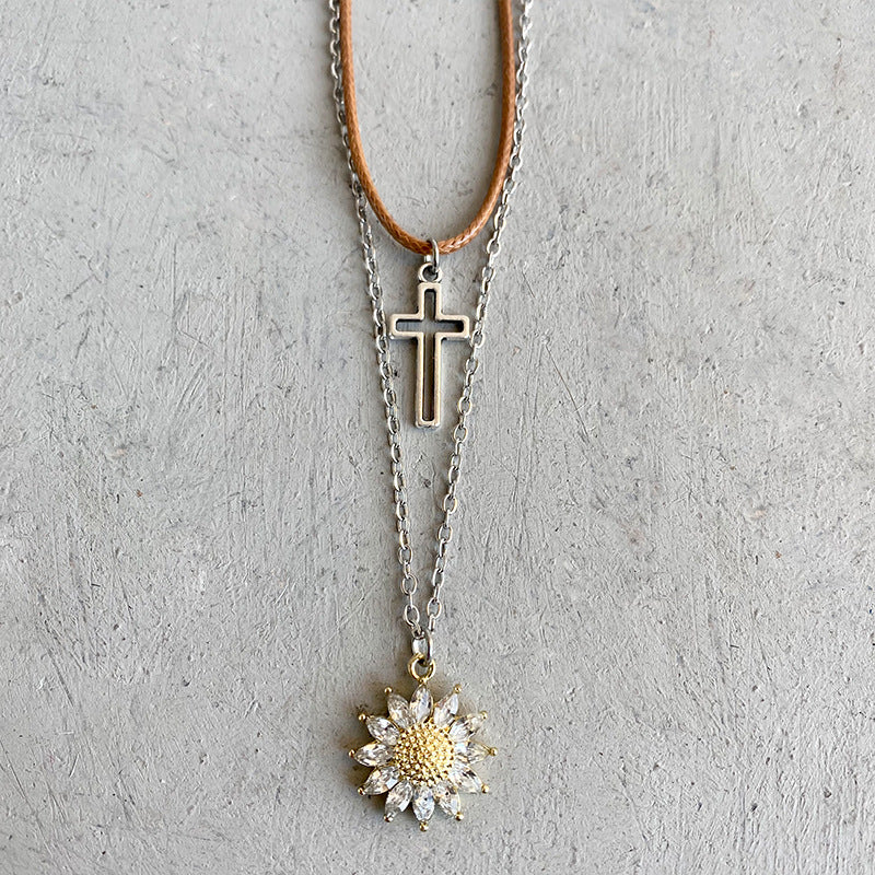 Layered necklace set with silver cross and gold sunflower charm with clear crystals.