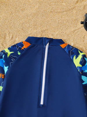 Baby rash guard with dinosaur print sleeves and quarter zip in navy blue.
