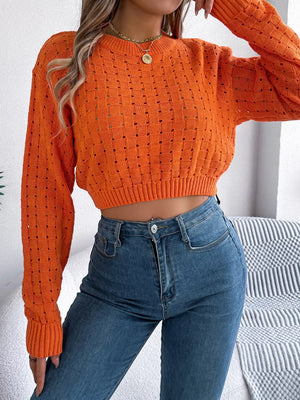 Orange openwork knit sweater with basketweave pattern and cropped length.