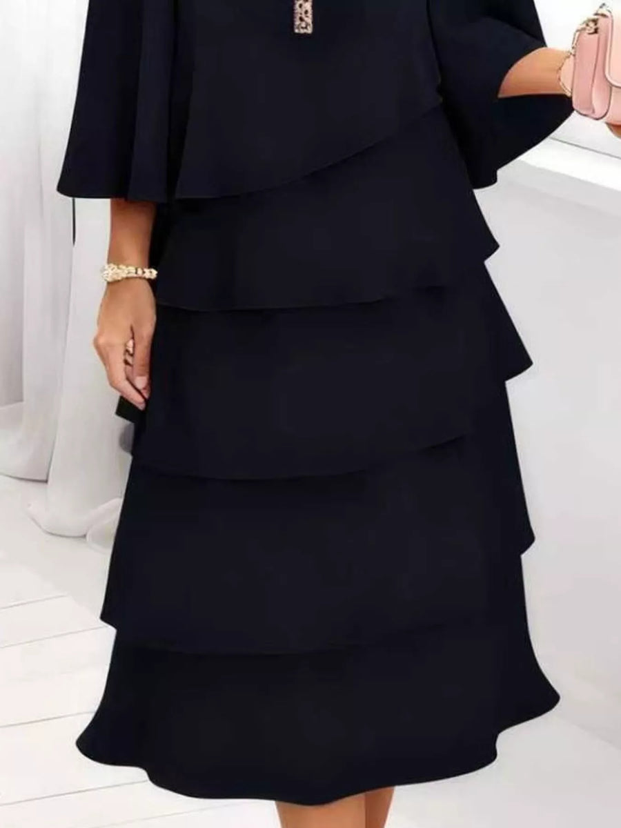 Black tiered ruffled dress with 3/4 sleeves and a bracelet.